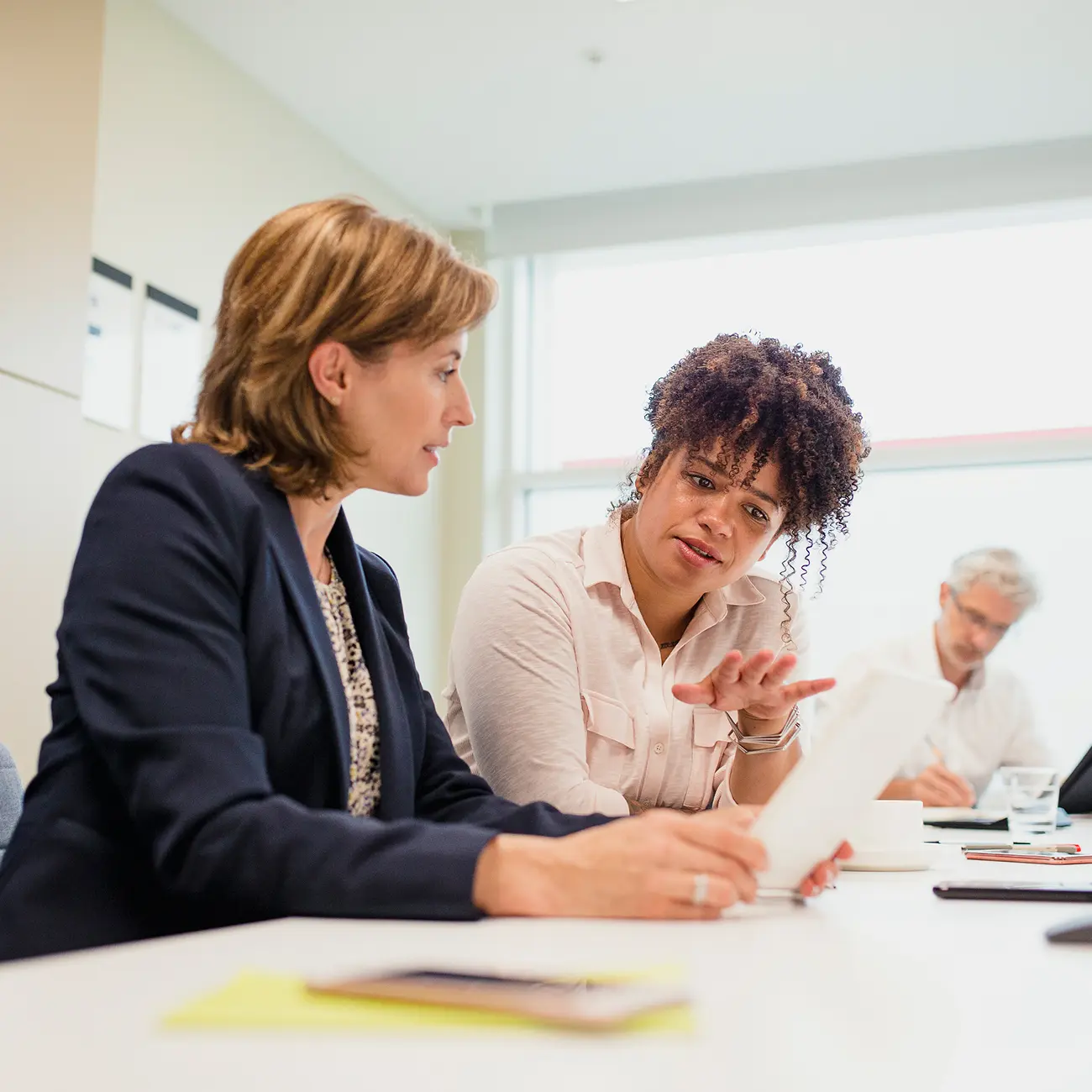 Two colleagues discussing a document at a meeting.