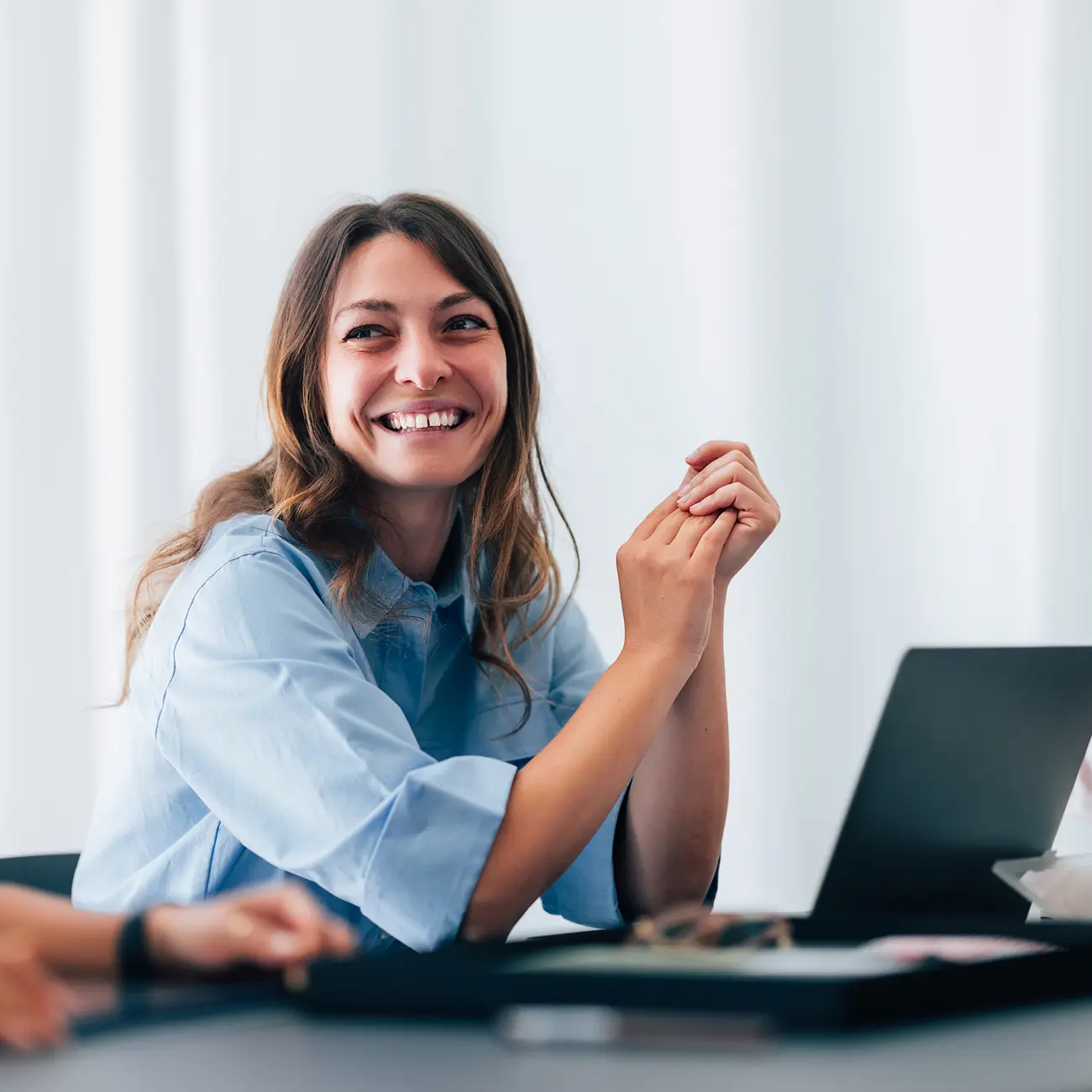 Woman smiling during a meeting with a laptop.