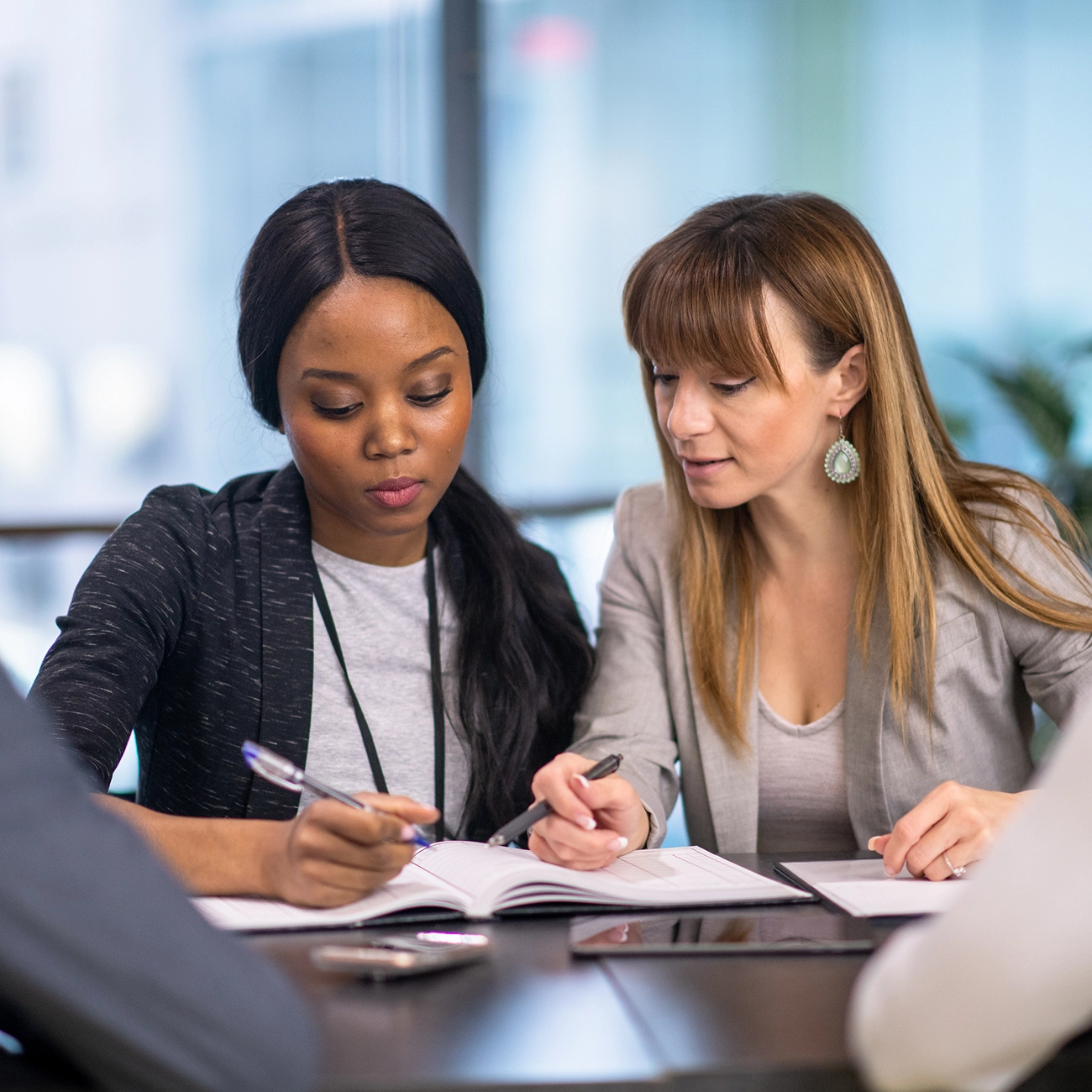 Two professionals taking notes during a meeting.