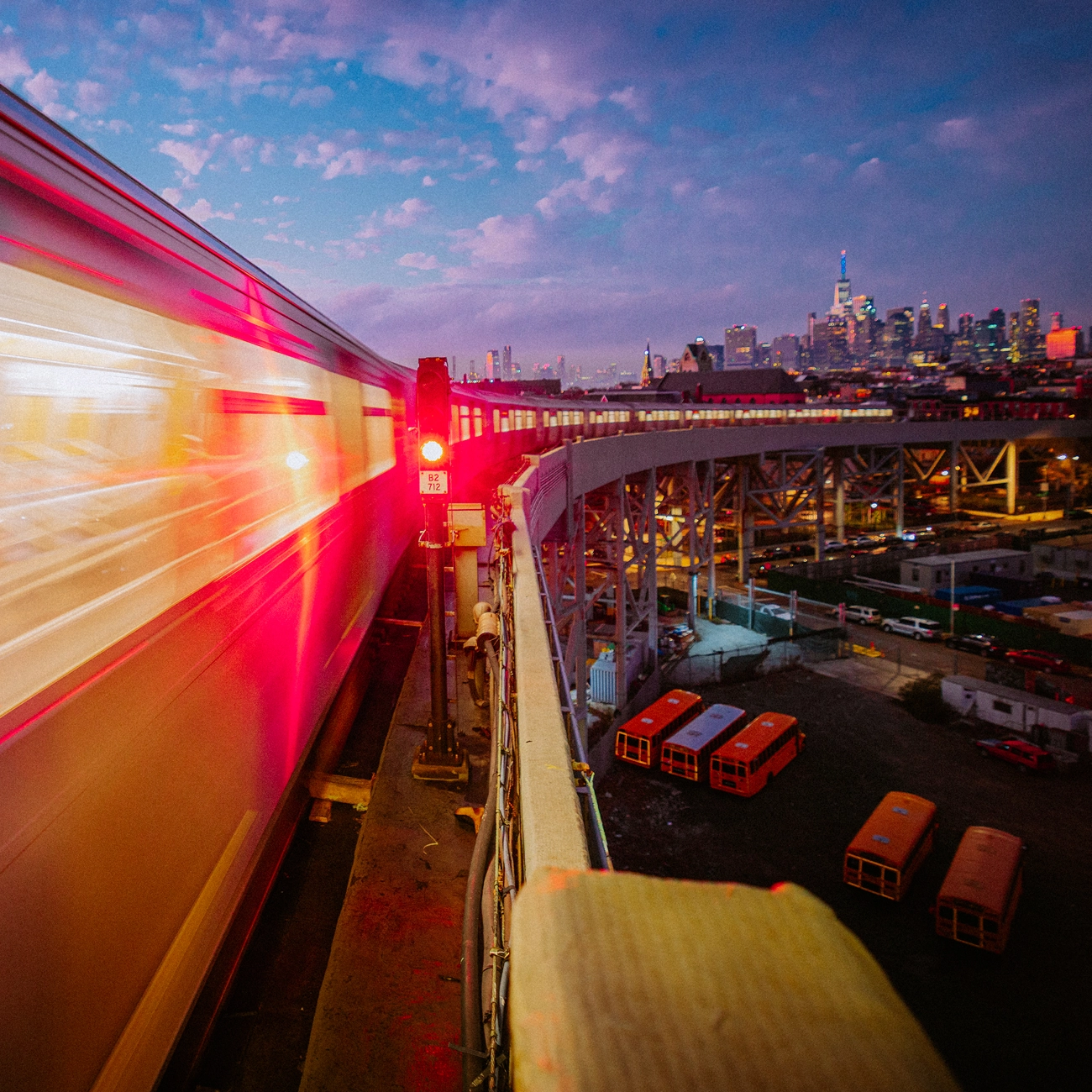 Train passing city skyline at dusk with motion blur.