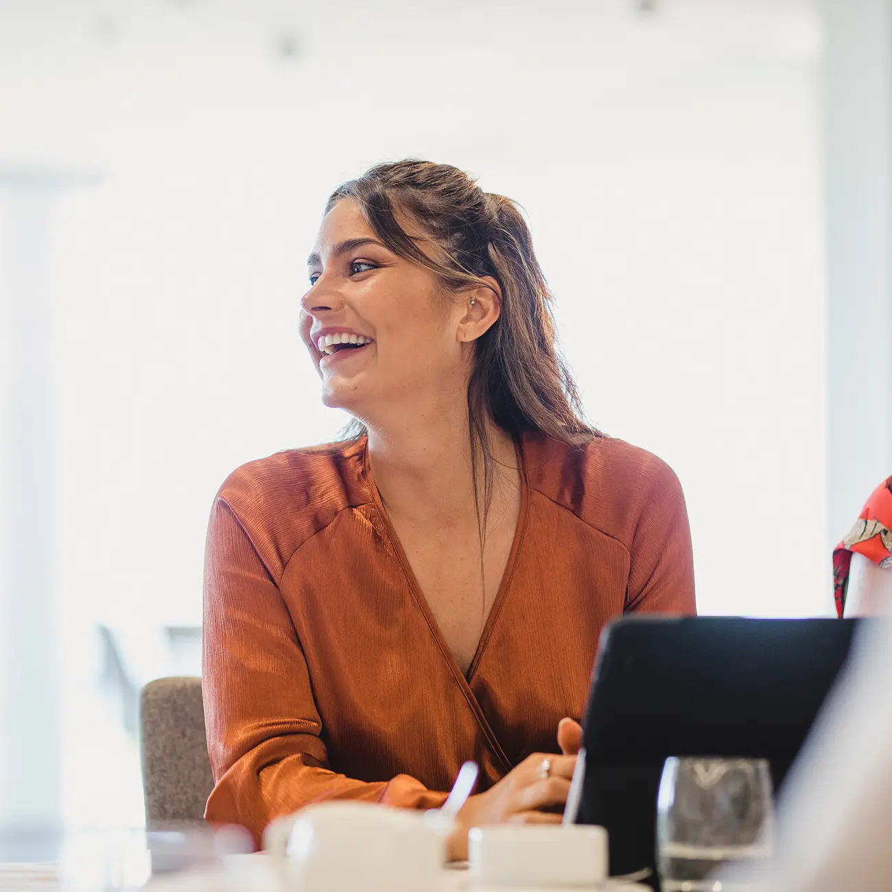 Woman smiling during a business meeting with tablet.